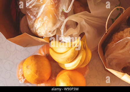 Carta e buste di plastica pacchetti con il cibo sulla tavola Foto Stock