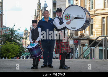 Glasgow, Regno Unito. 12 Ago, 2019. Di Glasgow international festival di tubazioni è iniziata oggi con una prestazione speciale dalla Scottish fuoco e di salvataggio novizio capretti Pipe Band. Ora nel suo sedicesimo anno, Piping Live, è il più grande festival del suo genere attrae 40.000 appassionati di musica, famiglie e appassionati da tutto il mondo per guardare oltre 5.000 pipers eseguire a 150 eventi in tutta la città. immagine di RODDY MACLEOD, Direttore del Festival CON EDDIE MCCLUSKEY ,di 17 anni su bass drum e EMILY GORMLEY, di anni 11, il più giovane membro della band Credito: Findlay/Alamy Live News Foto Stock