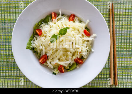 Thai piccante insalata di papaia Tam Som. Sfondo verde, bacchette sul lato. Quisine tradizionale della Thailandia e Laos. Foto Stock