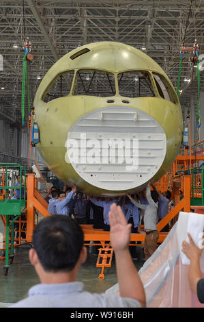 Ingegneri cinesi e tecnici direttamente una gru per spostare il naso della Cina il primo la produzione nazionale di fatto jet del passeggero aereo C919 presso lo stabilimento di Chengdu Foto Stock