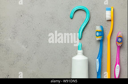 Il dentifricio a forma di punto interrogativo e di molti e diversi spazzolini da denti colorati. Concetto di come scegliere il giusto uno spazzolino da denti o come spazzolare i denti. Copia spazio per il testo. Foto Stock