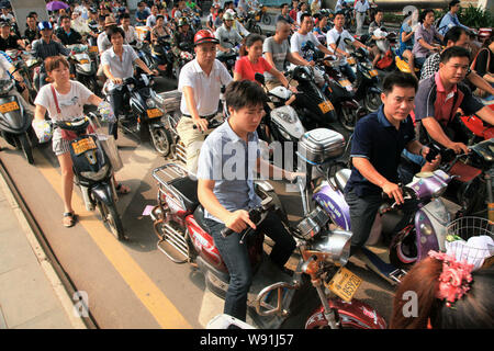 I ciclisti cinese di guidare la propria bici elettriche o scooter su una strada nel centro della città di Haikou, sud Chinas Hainan provincia, 16 settembre 2012. Foto Stock