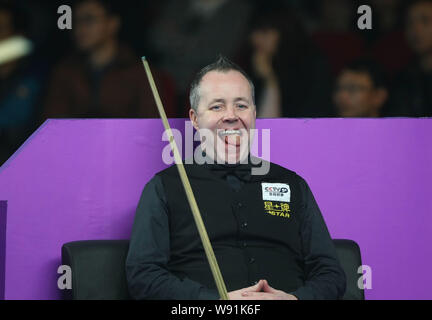 John Higgins della Scozia bastoni fuori la sua lingua è come egli orologi Joe Swail dell'Irlanda del Nord a giocare un colpo il loro match di primo turno del Mondo 2013 Foto Stock