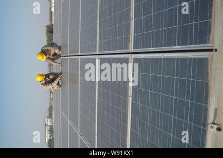 --FILE--lavoratori cinesi verificare appena installato pannelli solari sul tetto di un workshop presso una fabbrica tessile del gruppo Guanxing nella contea di Guanxian, Lia Foto Stock
