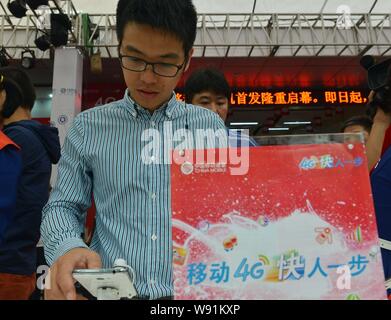 --FILE--un cliente cinese tenta di eseguire un 4G telefono cellulare presso un negozio di China Mobile in Hangzhou, est Chinas nella provincia di Zhejiang, 28 settembre 2013. Il Foto Stock