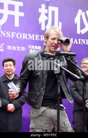 Regista americano Michael Bay pone con una lente durante una cerimonia di partenza per le riprese del suo film Transformers: Età di estinzione in cinese mainlan Foto Stock