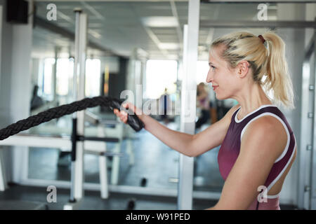 Sporty giovane donna nella battaglia di corda come allenamento Crossfit Training Foto Stock