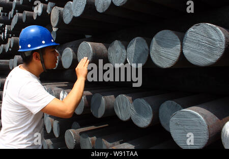 --FILE--un lavoratore cinese esamina una pila di acciaio grezzo in acciaio di un impianto di trasformazione in Liaocheng, est Chinas provincia di Shandong, 8 giugno 2013. Settori manifatturiero Foto Stock