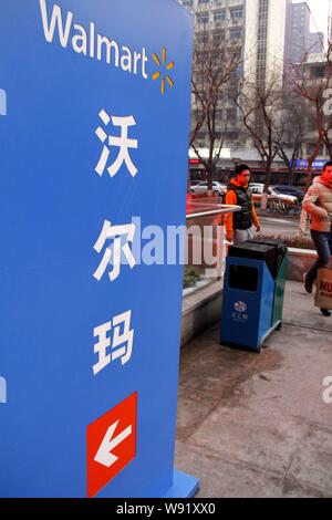 --FILE--pedoni a piedi passato una segnaletica di Wal-Mart supermercato in città di Shijiazhuang, porcellane del nord nella provincia di Hebei, 26 gennaio 2013. Il gigante Retail Wal Foto Stock