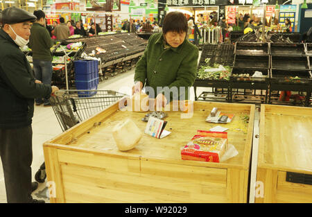 I clienti cinesi guardare quasi gli scaffali vuoti al supermercato Walmart programmati per chiudere in Luoyang city, porcellane centrale provincia di Henan, 5 Dicembre Foto Stock