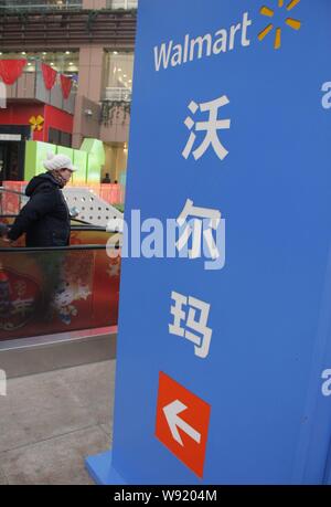 --FILE--pedoni a piedi passato una segnaletica di Wal-Mart supermercato in città di Shijiazhuang, porcellane del nord nella provincia di Hebei, 26 gennaio 2013. Il gigante Retail Wal Foto Stock