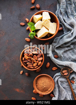 Le fave di cacao in polvere e burro di cacao su un nero lo sfondo di calcestruzzo Foto Stock