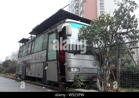 --FILE--Zhang, guardia di sicurezza Sun Jies moglie, guarda alla porta della sua casa, un convertito e alimentati a energia solare bus, nel Quartiere Songjiang, Shanghai, Chi Foto Stock