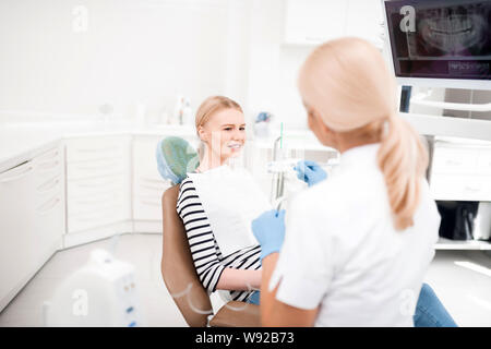 Paziente venga confuso seduta a dentisti in ufficio. Foto Stock