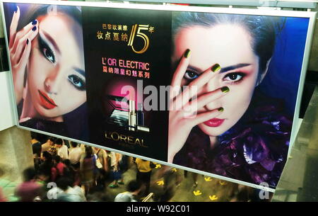 --FILE--pedoni camminare al di sotto di un annuncio per LOreal cosmetici in Cina a Shanghai, 10 maggio 2012. LOreal, i mondi più grande gruppo di cosmetici, sa Foto Stock