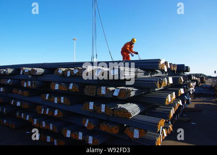 --FILE--un lavoratore cinese esamina una pila di rinforzo tondini di acciaio per essere esportato a un impianto siderurgico in Rizhao, est Chinas provincia di Shandong, 4 Octobe Foto Stock