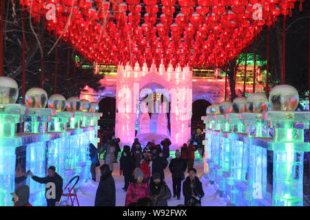 I visitatori a piedi passato sculture di ghiaccio sotto lanterne rosse durante la prova di funzionamento del quarantesimo di Harbin Lanterna di ghiaccio Arte Fiera nella città di Harbin, nordest mento Foto Stock