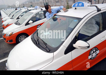 Il cinese i tassisti spolverare il loro taxi elettrico in corrispondenza di una stazione di carica nel Distretto di Tongzhou, Pechino, Cina, 29 settembre 2013. Pechino è expecte Foto Stock