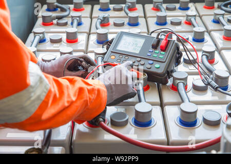 Specialista elettricista ispezionare e controllare la tensione e la resistenza interna delle batterie utilizzando la batteria per la manutenzione preventiva, offshore del petrolio e del gas oc Foto Stock