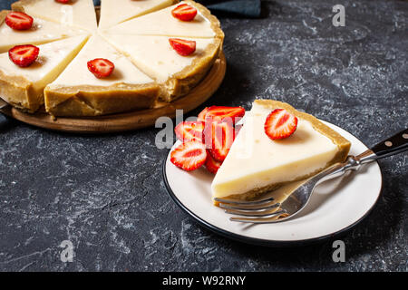 Cheesecake fatti in casa con fragole fresche a fette nero su sfondo di pietra Foto Stock