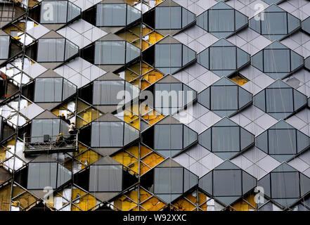 Lavoratori cinesi installare il vetro sulla facciata del sette-star hotel Wanda regnare Wuhan, in costruzione nella città di Wuhan, central Chinas Hubei provinc Foto Stock
