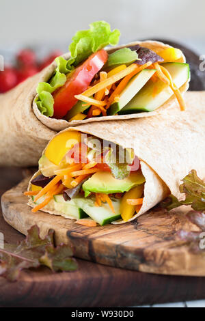 Un sano il pranzo o la cena di vegano / vegetariano wrap fatta con argula lattuga, pomodori a fette, cetrioli, avocado, peperoni e carote. Foto Stock