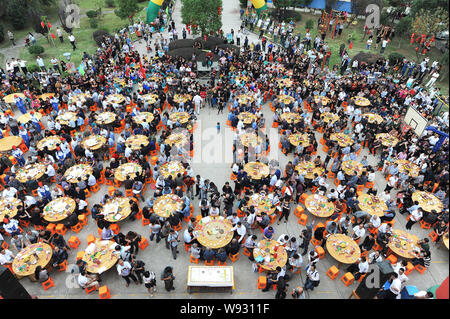 Anziani locali alle persone di mangiare torte e altro cibo intorno a tavoli presso un collettivo di celebrazione di compleanno nel villaggio Dongxidan, Dongcheng città, città Linhai, ea Foto Stock