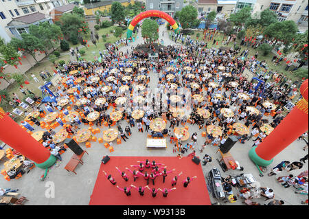 Anziani locali alle persone di mangiare torte e altro cibo intorno a tavoli presso un collettivo di celebrazione di compleanno nel villaggio Dongxidan, Dongcheng città, città Linhai, ea Foto Stock