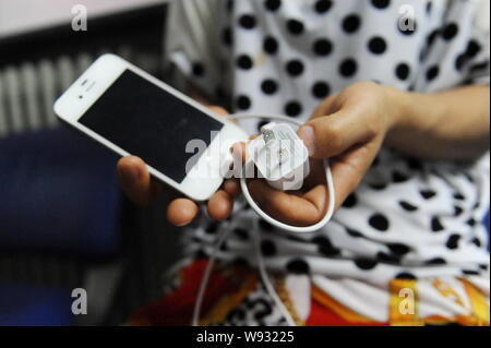 --FILE--una donna cinese mostra un Apple iPhone 4S smartphone e un alimentatore USB a Pechino in Cina, 19 luglio 2013. La morte di una donna cinese p. Foto Stock