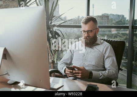 Imprenditore rendendo chiamata seduto alla scrivania in ufficio. Foto Stock