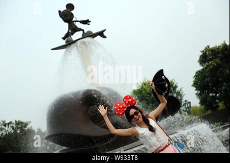 --FILE -- un turista pone con una fontana con Micky Mouse a Hong Kong Disneyland Resort di Hong Kong, Cina, 22 luglio 2012. Le ultime escal Foto Stock