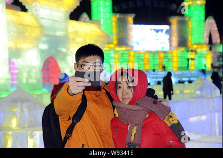 Una coppia giovane prende selfies davanti a sculture di ghiaccio al XV di Harbin ed al Mondo del Ghiaccio e della neve nella città di Harbin, nordest Chinas Provincia di Heilongjiang, Foto Stock