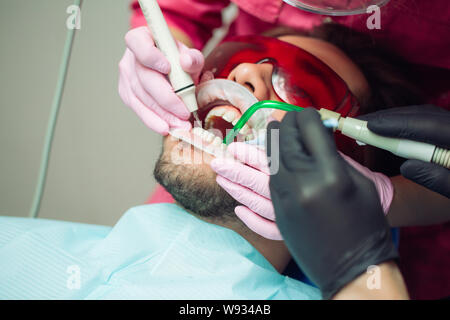 Pulizia dei denti professionale. Dentista pulisce i denti di un paziente di sesso maschile. Foto Stock