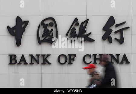 --FILE--due pedoni a piedi passato una segnaletica della Banca di Cina nella città di Nantong, est Chinas provincia dello Jiangsu, 23 dicembre 2012. La Bank of China Ltd. ha Foto Stock