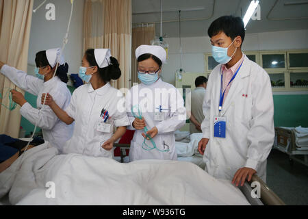 Il cinese lavoratori medici chirurgici da indossare maschere viso esaminare un paziente presso un ospedale in Cina a Shanghai, 22 luglio 2013. Circa 70 ospedali e quasi Foto Stock