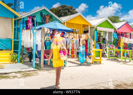 Donna che guarda i negozi di souvenir e colorato cottage di legno, Long Bay Beach, Antigua, dei Caraibi Foto Stock