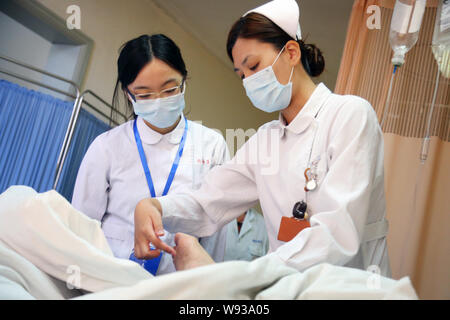 Il cinese lavoratori medici chirurgici da indossare maschere viso esaminare un paziente presso un ospedale in Cina a Shanghai, 22 luglio 2013. Circa 70 ospedali e quasi Foto Stock