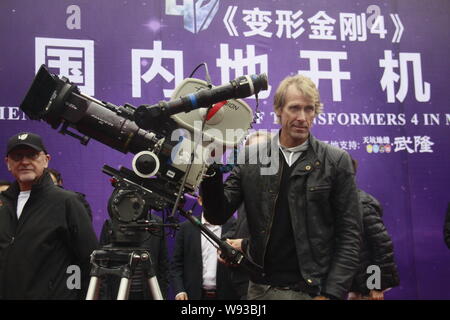 Regista americano Michael Bay pone con una videocamera durante una cerimonia di partenza per le riprese del suo film Transformers: Età di estinzione in cinese Foto Stock