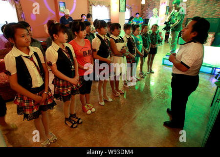 Manager cinese Yang Qunhui, destra, dà istruzioni al suo dwarf camerieri e cameriere presso l'isola felice favola ristorante a tema in Zhengzho Foto Stock