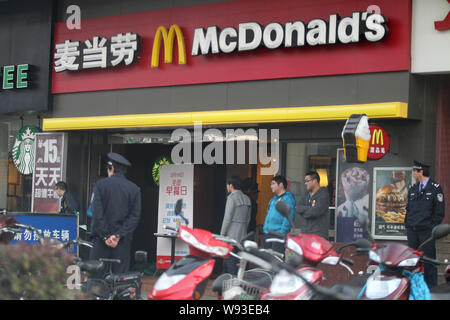 Cinese il personale di sicurezza guardia accanto ai residenti locali in coda per libero McMuffins essendo distribuite in un McDonalds un fast food ristorante a Nanto Foto Stock