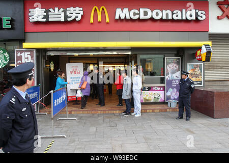 Cinese il personale di sicurezza guardia accanto ai residenti locali in coda per libero McMuffins essendo distribuite in un McDonalds un fast food ristorante a Nanto Foto Stock