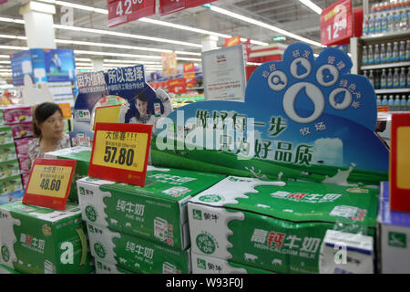 --FILE--un cliente passeggiate passato cartoni di Mengniu puro latte e Mengniu High-Calcium latte ad un supermercato di Nantong, est Chinas provincia dello Jiangsu, 27 Foto Stock