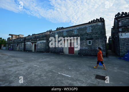 --FILE--un abitante di un villaggio passeggiate passato del Kaiping Diaolou le case di un villaggio del Kaiping, Jiangmen city, a sud Chinas nella provincia di Guangdong, Agosto 2012. Essi sono Foto Stock