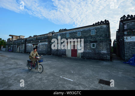 --FILE--un ciclista passa del Kaiping Diaolou le case di un villaggio del Kaiping, Jiangmen city, a sud Chinas nella provincia di Guangdong, Agosto 2012. Essi sono t Foto Stock