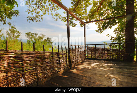 Essendo su un vecchio balcone di legno nella foresta, durante la soleggiata giornata estiva. Foto Stock