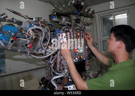 L'agricoltore cinese Tao Xiangli accende gli interruttori sul retro del suo robot costituita da rottami a casa a Pechino, in Cina, il 16 maggio 2013. Tao Xiangli, 37- Foto Stock