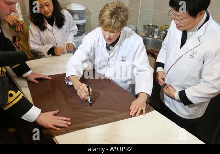 Sharon Johnston, la moglie di Davide Johnston, attuale governatore generale del Canada, centro autografi su un grembiule in amicizia panificio in Nanjing, Cina orientale Foto Stock