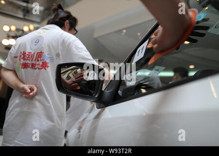 Concorrenti cinesi tenere le mani su una Volkswagen Polo GTI durante una mano-su-auto competizione endurance a Super Brand Mall in Lujiazui finanziario Foto Stock