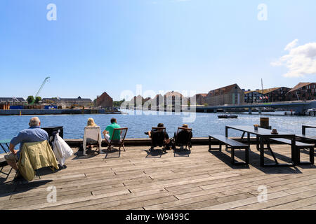 Copenhagen, Danimarca - 11 Luglio 2019: Alcune persone sono in appoggio sul lungomare di Nyhavn canal in estate Foto Stock