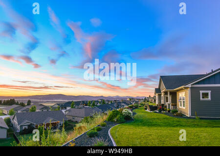 Un bellissimo tramonto colorato di rosa e aqua blu il colore del cielo sopra un tipico american suddivisione sul pendio di una collina in Spokane Washington. Foto Stock
